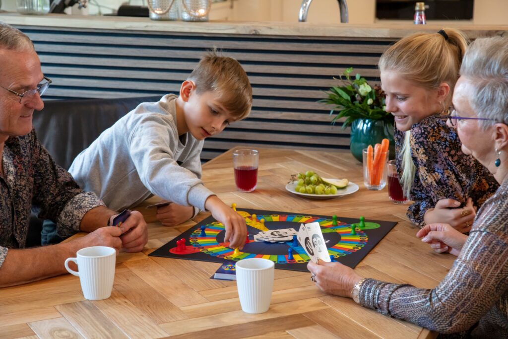 En familie sidder ved et bord og spiller brætspillet Partners.